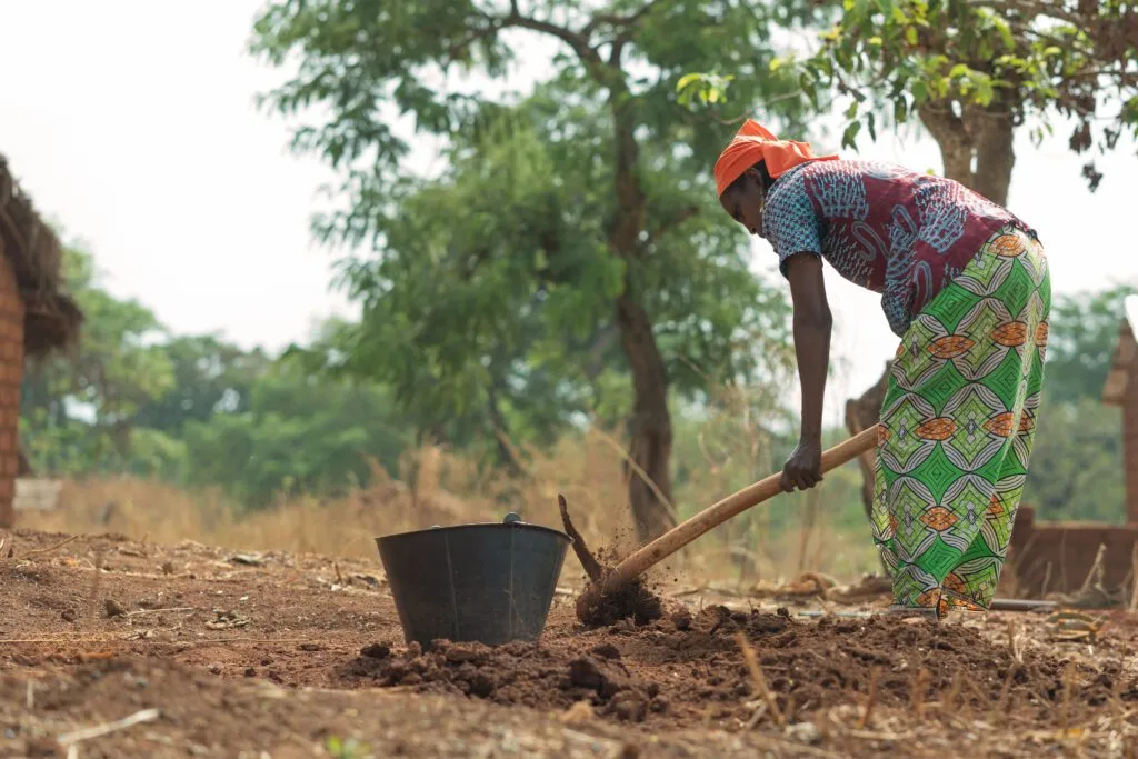Mujer fulani cavando en la tierra con un pico en África Occidental | SIM International