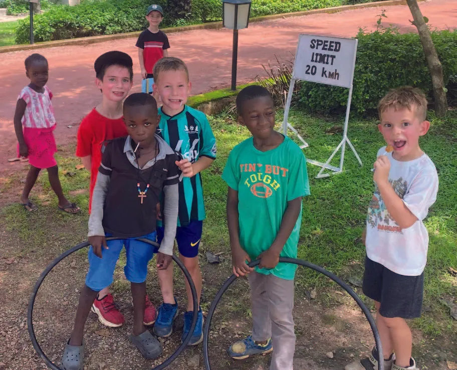 Un grupo de niños posando de manera juguetona en un terreno de césped, algunos sosteniendo hula hoops con alegría